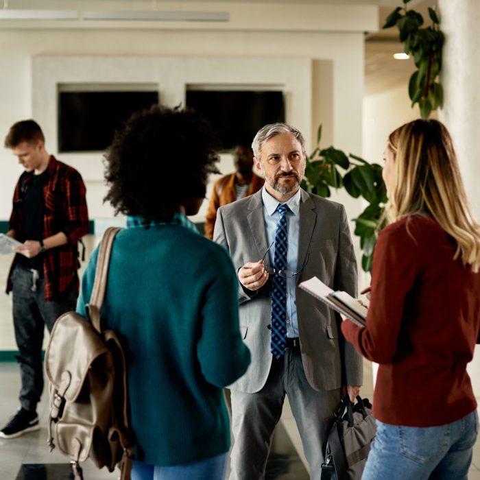 mature-professor-talking-to-female-students-at-uni